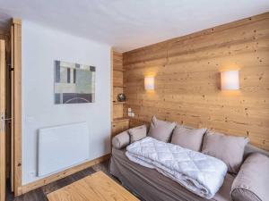 a couch in a room with a wooden wall at Studio confortable, casier à ski, proche pistes, Méribel - FR-1-355-164 in Les Allues