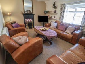 a living room with leather furniture and a table at The Plover in Holt