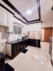 a kitchen with white cabinets and black counter tops at EA4 Furnished Transient Room Apartment House Walking Distance to SM Ecoland & Davao Coastal Road and Near Ecoland Bus Terminal in Davao City