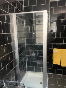 e bagno piastrellato nero con vasca e doccia. di The Oxford St Stay a Londra