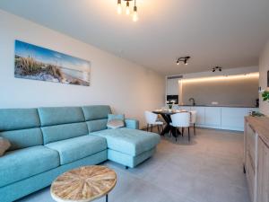 a living room with a blue couch and a table at Apartment Elyana with balcony by Interhome in Blankenberge