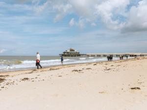 people walking on the beach with a pier in the background at Apartment Elyana with balcony by Interhome in Blankenberge