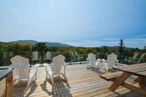 a deck with white chairs and a wooden table and a picnic table at room with shared bathrooms 883 Shefford in Bromont +14 photos