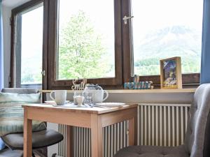 une table et une chaise dans une pièce avec des fenêtres dans l'établissement Apartment Studio Esche 4 by Interhome, à Ellmau 56 autres photos
