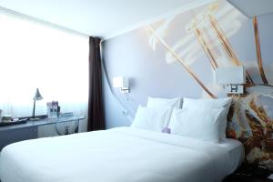 Cette chambre comprend un grand lit blanc et une fenêtre. dans l'établissement Mercure Paris Malakoff Parc des Expositions, à Malakoff