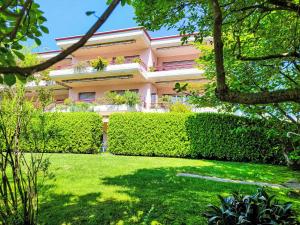 a pink building with a hedge in front of a yard at Apartment Caslago by Interhome in Caslano