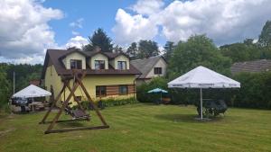 a yard with a house with an umbrella and a swing at Pokoje na Wiejskiej in Nałęczów