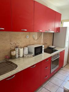 a kitchen with red cabinets and a microwave at Apartment MJ in Čapljina