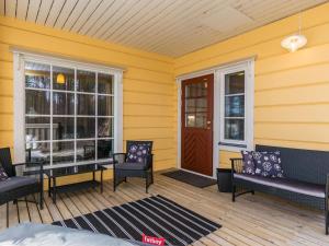 ein gelbes Haus mit Stühlen und einer Tür auf einer Veranda in der Unterkunft Holiday Home Villa niemelänranta by Interhome in Puumala