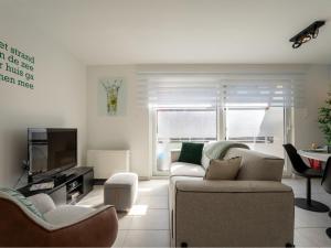 a living room with a couch and a tv at Apartment Havenhuys IV by Interhome in Bredene