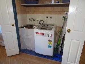 une cuisine avec un évier et une machine à laver dans l'établissement Kindlewood Cottage, à Esperance 8 autres photos