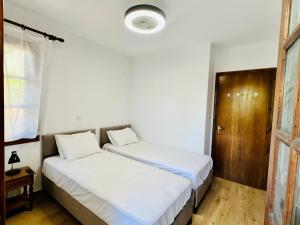 a bedroom with two beds and a wooden door at Elgi Cottage in Chrysi Ammoudia