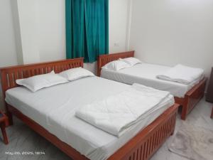 two beds in a room with green curtains at SSN Residency in Tiruvannāmalai +5 photos