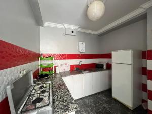 a kitchen with red and white walls and a white refrigerator at Younes residence in Asilah