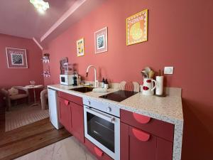 a red kitchen with a sink and a counter top at LE LOVE-ROOM, Jacuzzi, Hyper-centre in Mâcon