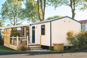 a tiny house with a porch and stairs at Camping calme En Charente Maritime in Surgères