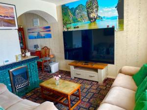 a living room with a large television and a fireplace at Northern homestay between High Peak & Manchester in Hadfield