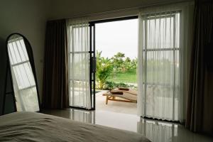 a bedroom with a bed and a large sliding glass door at Villa Alaya No 4 in Cemagi