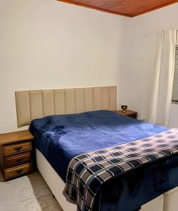 a bedroom with a bed with a blue comforter at Vila de Casas de Campo Rústica e Aconchegante na Mata Atlântica in Juquitiba