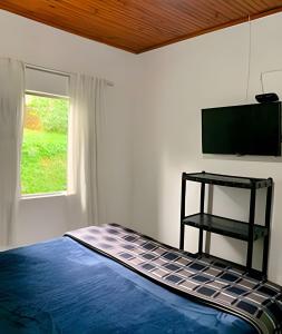 a bedroom with a bed with a flat screen tv at Vila de Casas de Campo Rústica e Aconchegante na Mata Atlântica in Juquitiba