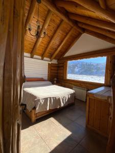 a bedroom with a bed in a wooden house at Lodge Copahue Expeditions in Caviahue