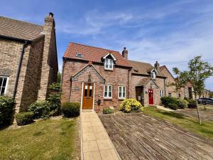 a brick house with a red door and a driveway at Gingerbread Cottage in Filey