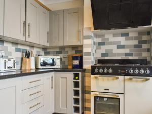 a kitchen with white cabinets and black appliances at Pilchard Cottage in Scarborough