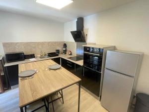 a kitchen with a wooden table and a refrigerator at Le Briand in Tulle