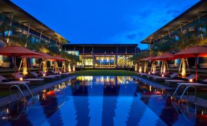 a pool with chairs and umbrellas in front of a building at Amari Buriram United in Buriram