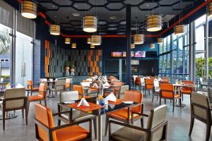 a dining room with tables and chairs and windows at Amari Buriram United in Buriram