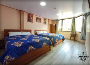 a bedroom with two beds and a window at Hostal California AC-DC in Baños
