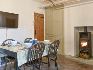 a dining room with a table with chairs and a fireplace at Campbell Cottage in Windermere