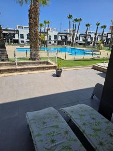een terras met twee kussens en een zwembad bij Sunny Ground floor bungalow opposite the swimming pool in Orihuela