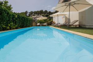 a large blue swimming pool with an umbrella at CIM Apartments in Olivella