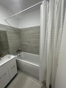 a bathroom with a white tub and a sink and a shower at Suba's Apartment Free Parking Self Check-in in Timişoara +33 photos