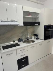 a white kitchen with a sink and a microwave at Suba's Apartment Free Parking Self Check-in in Timişoara