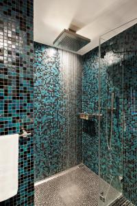 W łazience znajduje się przeszklona kabina prysznicowa wyłożona niebieskimi kafelkami. w obiekcie Les Rhodos w mieście Clusaz