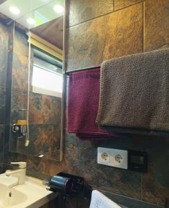 een badkamer met een wastafel, een spiegel en handdoeken bij Gästehaus "Säntis" in Carnikava