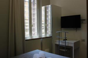a bedroom with a bed with a television and windows at Rooms Piramide 1 in Rome
