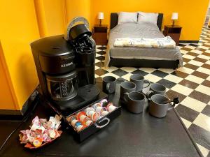 a coffee maker and cups on a table next to a bed at Trailside Furnished Apartment 