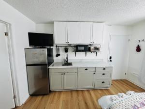 a kitchen with white cabinets and a stainless steel refrigerator at NookSide Nest Studio Queen Parking Kitchenette in Carleton Place
