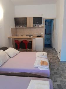 Un dormitorio con una cama con dos taburetes y una cocina. en Apartments Masa, en Sutomore