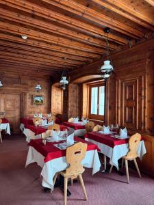 una sala da pranzo con tavoli e sedie rossi e bianchi di Hotel Corona a Vicosoprano