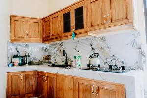 a kitchen with wooden cabinets and marble counter tops at Kurniawan By Travelink in Dieng