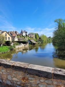 a view of a river with houses in the background at Sac des Vertues Bordure Rivière in Beaumont-sur-Sarthe