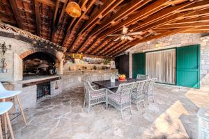 eine Terrasse mit einem Tisch, Stühlen und einem Kamin in der Unterkunft Holiday Home Sarbunara in Milna