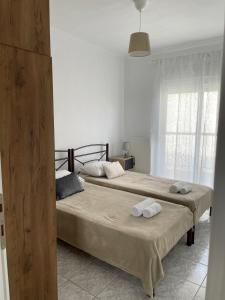 two beds in a white room with towels on them at Isolde Apartment in Kallithea Halkidikis
