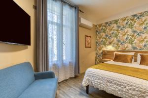 a bedroom with a bed and a tv and a couch at Hôtel Mistral Saint Roch in Montpellier