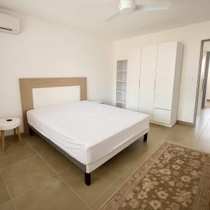 a bedroom with a large white bed and a rug at Appartement cosy - extérieur et parking in La Trinité