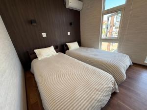 two beds in a small room with a window at Full House Furano in Furano